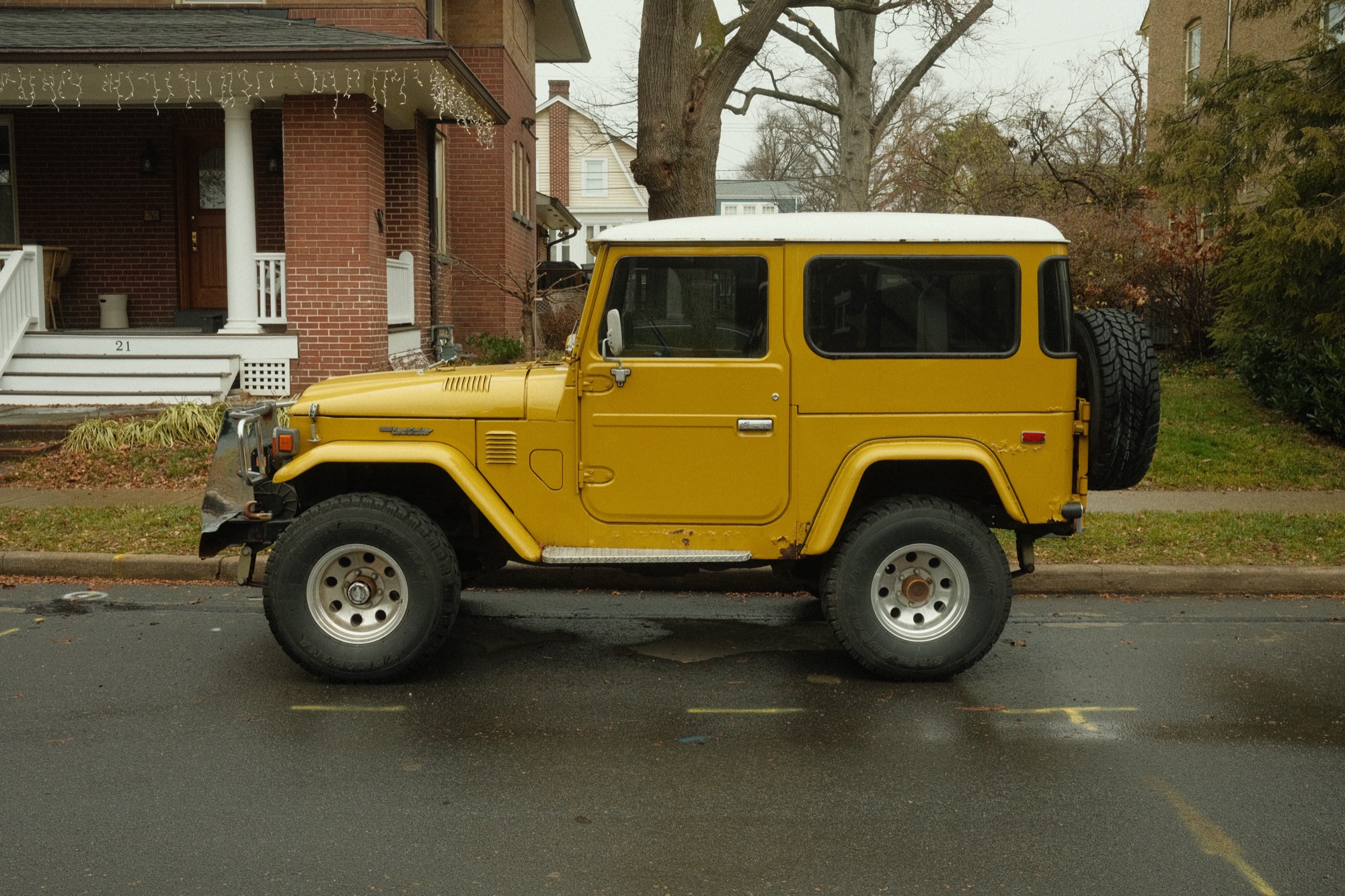 A yellow vintage Toyota FJ40 Land Cruiser in profile